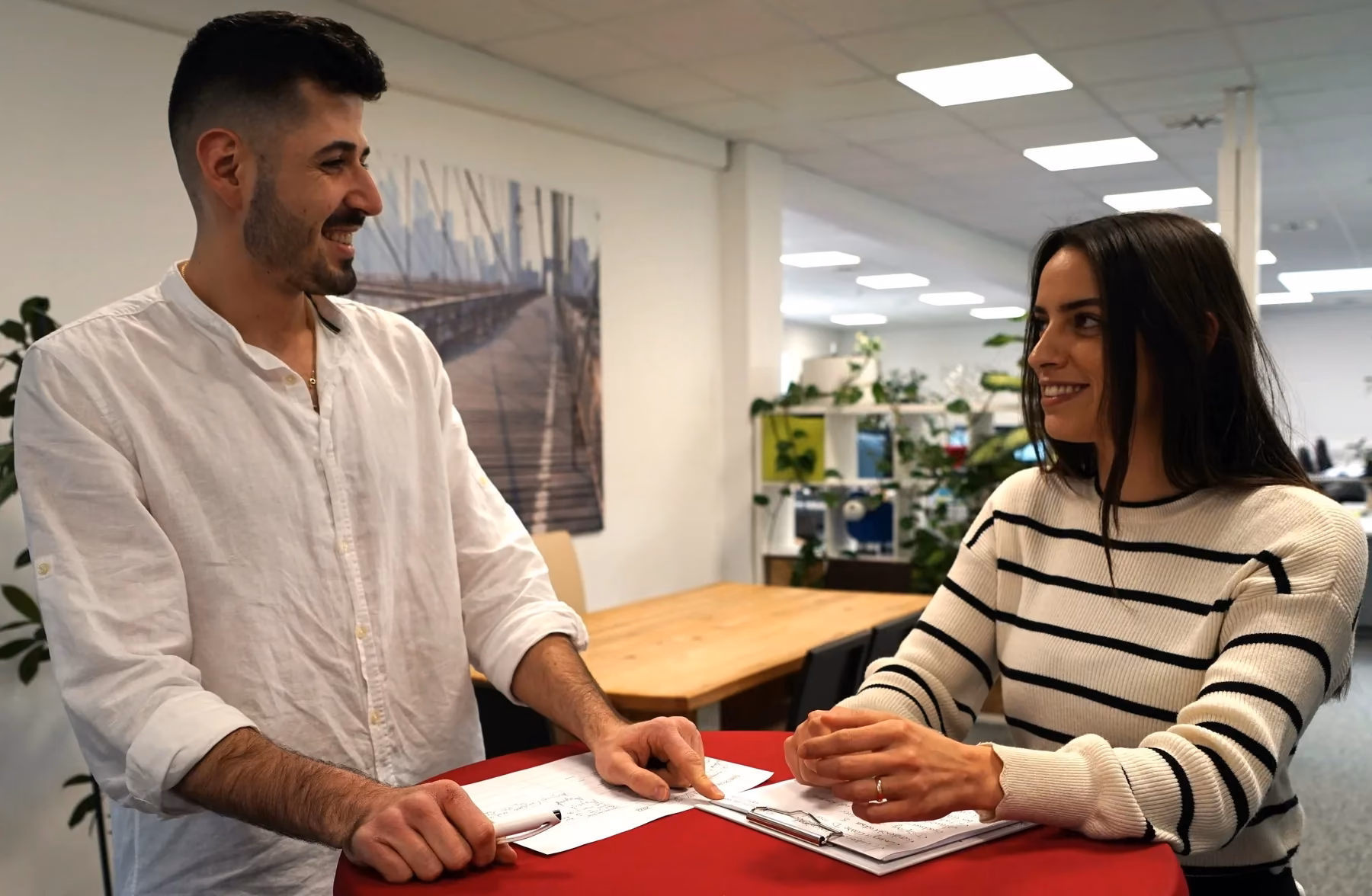 Zwei Personen im Gespräch an einem Besprechungstisch im Büro.